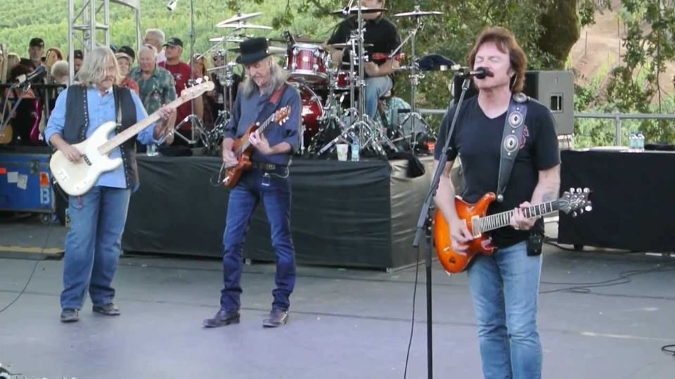 Tom Johnston singing and playing guitar with the Doobie Brothers on stage.